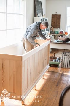 a man standing on top of a wooden counter in a kitchen next to a window