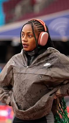 a woman with dreadlocks wearing headphones on the side of her face and looking off into the distance