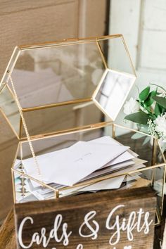 a wooden box filled with cards and gifts on top of a table next to flowers