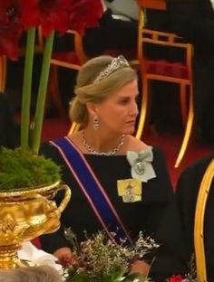 the queen and prince are sitting next to each other in front of a vase with flowers