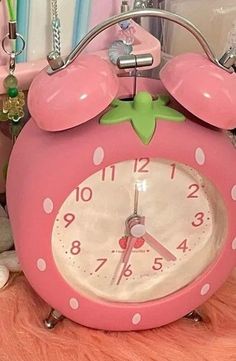 a pink alarm clock sitting on top of a table next to stuffed animals and toys