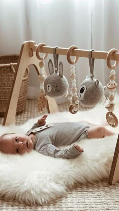 a baby laying on top of a white rug in front of a wooden crib