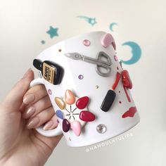 a hand holding a coffee mug with nail polishes and manicures on it