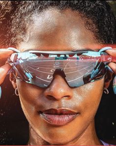 a woman with sunglasses on her face looking at the camera and holding it up to her eye