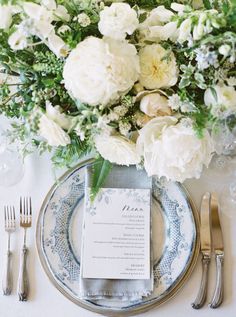 a table setting with white flowers and silverware