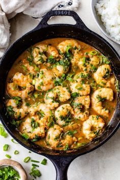 a skillet filled with shrimp and vegetables next to rice