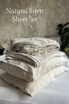 a pile of linen sitting on top of a bed next to a potted plant