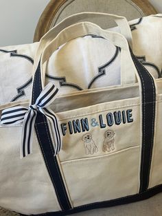 a white bag with blue trim and two dogs on the front is sitting on a chair