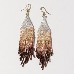 two tone gold and silver earrings with fringes hanging from hooks on a white background