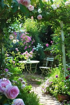 a garden with pink and white flowers on the ground, tables and chairs in the middle