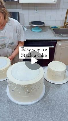 a woman is decorating two cakes with white frosting