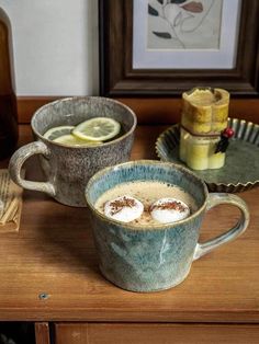 two mugs filled with liquid sitting on top of a wooden table