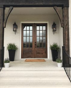 a front door with two planters on the steps and an entry way leading up to it