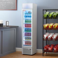 a refrigerator filled with drinks and snacks next to a wall mounted chalkboard on the wall