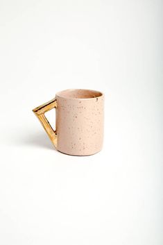 a white and gold coffee mug with a handle on the side, against a white background