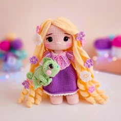 a crocheted doll holding a stuffed animal in her arms and wearing a purple dress