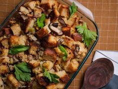 a casserole dish with bread, mushrooms and parsley in it on a table