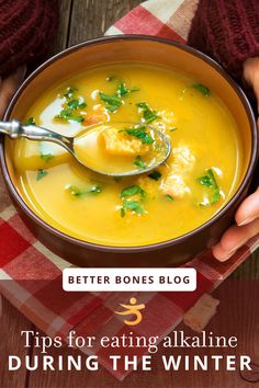 a person holding a spoon full of soup with the words tips for eating alkaine during the winter