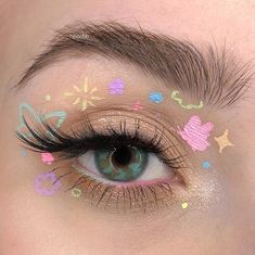 This look is a playful and whimsical take on butterfly eye makeup, perfect for those who enjoy a more simple and fun aesthetic. The eyelids are adorned with a light, shimmery gold shadow as a base. Over this, tiny pastel doodles, including butterflies, stars, and hearts, are drawn using pastel shades of pink, blue, green, and yellow. This look mimics the appearance of a child’s coloring book, giving it a unique and creative flair. The pastel colors create a soft, easy look that is both cute and eye-catching, making it ideal for casual outings or a day at the park.   Photo credit by: @ttd_eye Pastel Doodles, Butterfly Eye Makeup, Eyeliner Idea, Tattoo Wings, Tips For Drawing, Hippie Makeup, Creative Butterfly, Artsy Makeup, Pastel Makeup