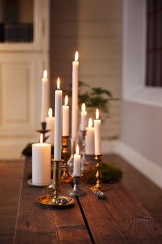 candles are lit on a wooden table in front of a wall with white walls and wood flooring