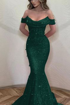 a woman in a green dress posing for the camera with her hands on her hips