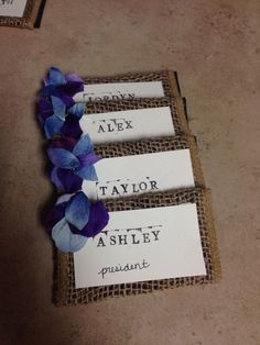 three name tags with purple and blue flowers attached to burlocks on the floor