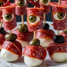 an appetizer with olives, cheese and meat on sticks is displayed in front of the camera