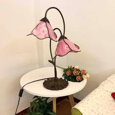 a lamp that is sitting on top of a table next to a flower pot with flowers in it