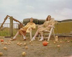 two women sitting on lawn chairs in front of pumpkins