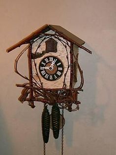 a clock that is on the wall with chains hanging from it's sides and two hands