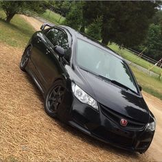 a black car parked on top of a dirt road