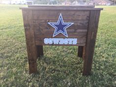 a wooden sign with the word cowboys painted on it in front of a grassy field