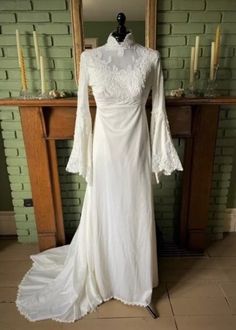 a white wedding dress on display in front of a fireplace