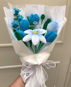 a person holding a bouquet of blue and white flowers