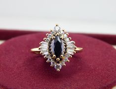 a diamond and black stone ring sitting on top of a red velvet pad