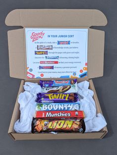 a box filled with lots of candy sitting on top of a gray floor next to a sign