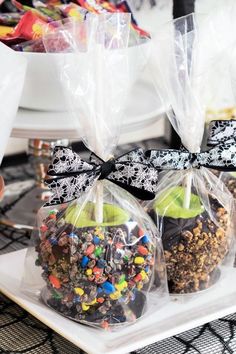 two bags filled with chocolate covered apples on top of a white plate and black ribbon