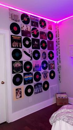 a bed room with a neatly made bed and lots of vinyl records on the wall