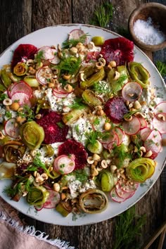 a salad with radishes, cucumbers and nuts on a white plate