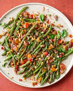 a white plate topped with asparagus and other veggies on top of a red table