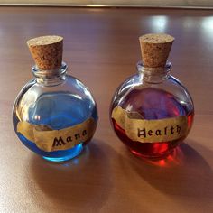 two small bottles with labels on them sitting on a wooden counter top next to each other