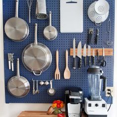 a kitchen wall with pots, pans and utensils hanging on the pegboard