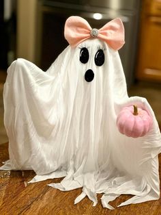 a white ghost with a pink pumpkin in it's hand on a wooden table