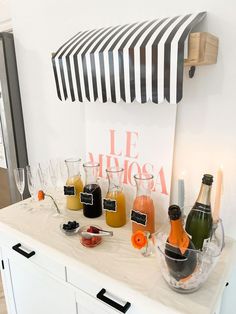 an assortment of drinks and condiments sit on a white counter in front of a black and white striped sign