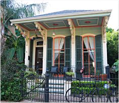 a bicycle is parked in front of a house with green shutters and red trim