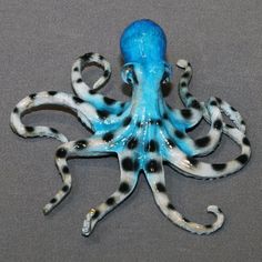 an octopus figurine with black and white spots on it's body, sitting on a gray surface