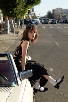 a woman sitting on the hood of a car