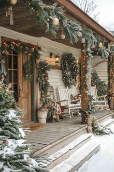 a porch covered in christmas wreaths and lights with rocking chairs on the front porch