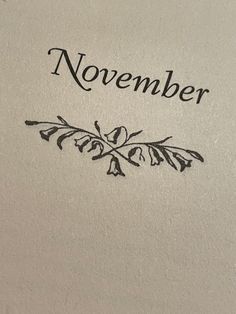 the word november written in black ink on a piece of paper with an image of leaves