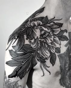 the back of a man's shoulder with flowers and leaves on it